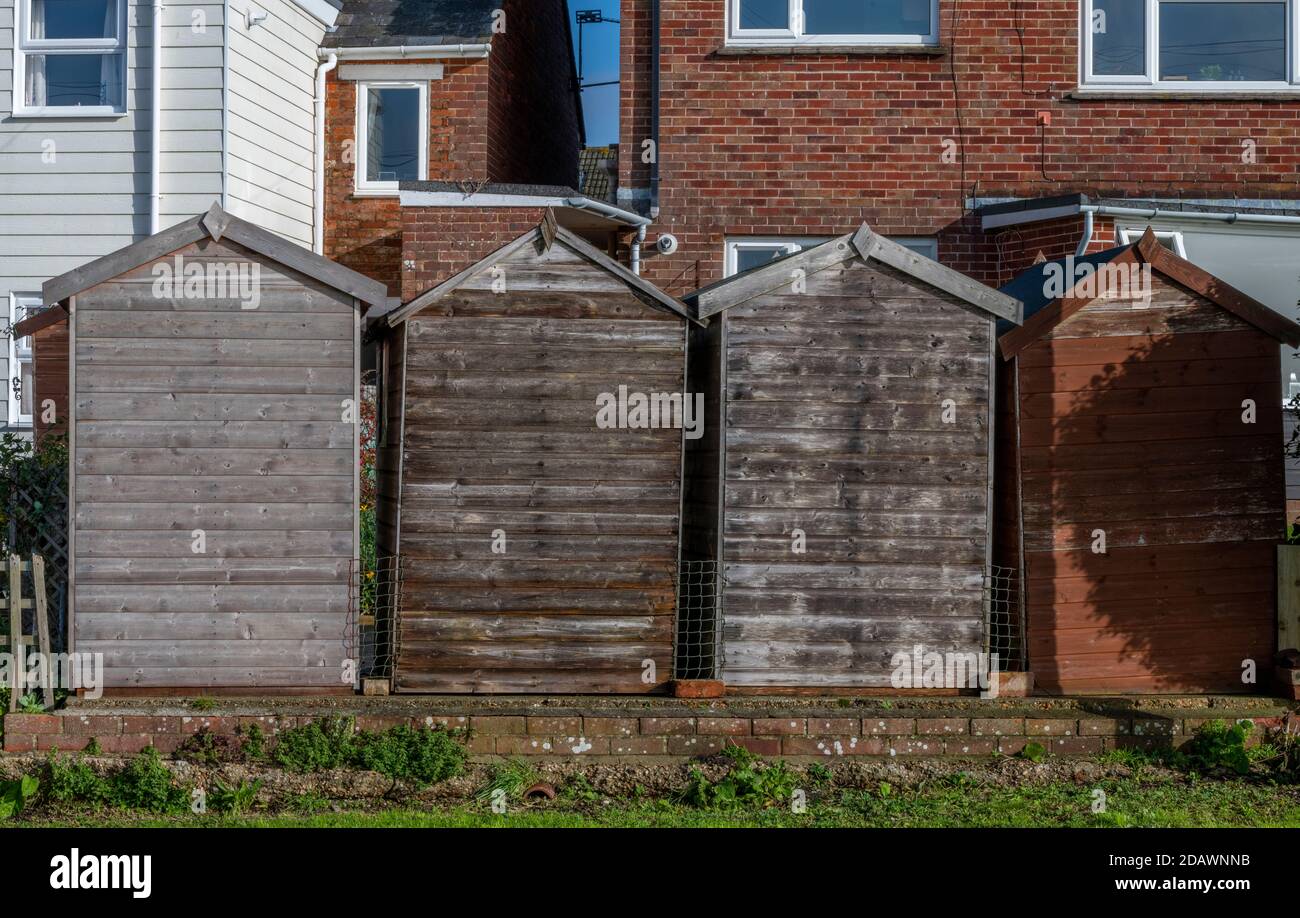 Una fila di capannoni giardino fuori di una casa tutte le stesse dimensioni facendo una linea o modello di cabine di deposito giardino. Foto Stock