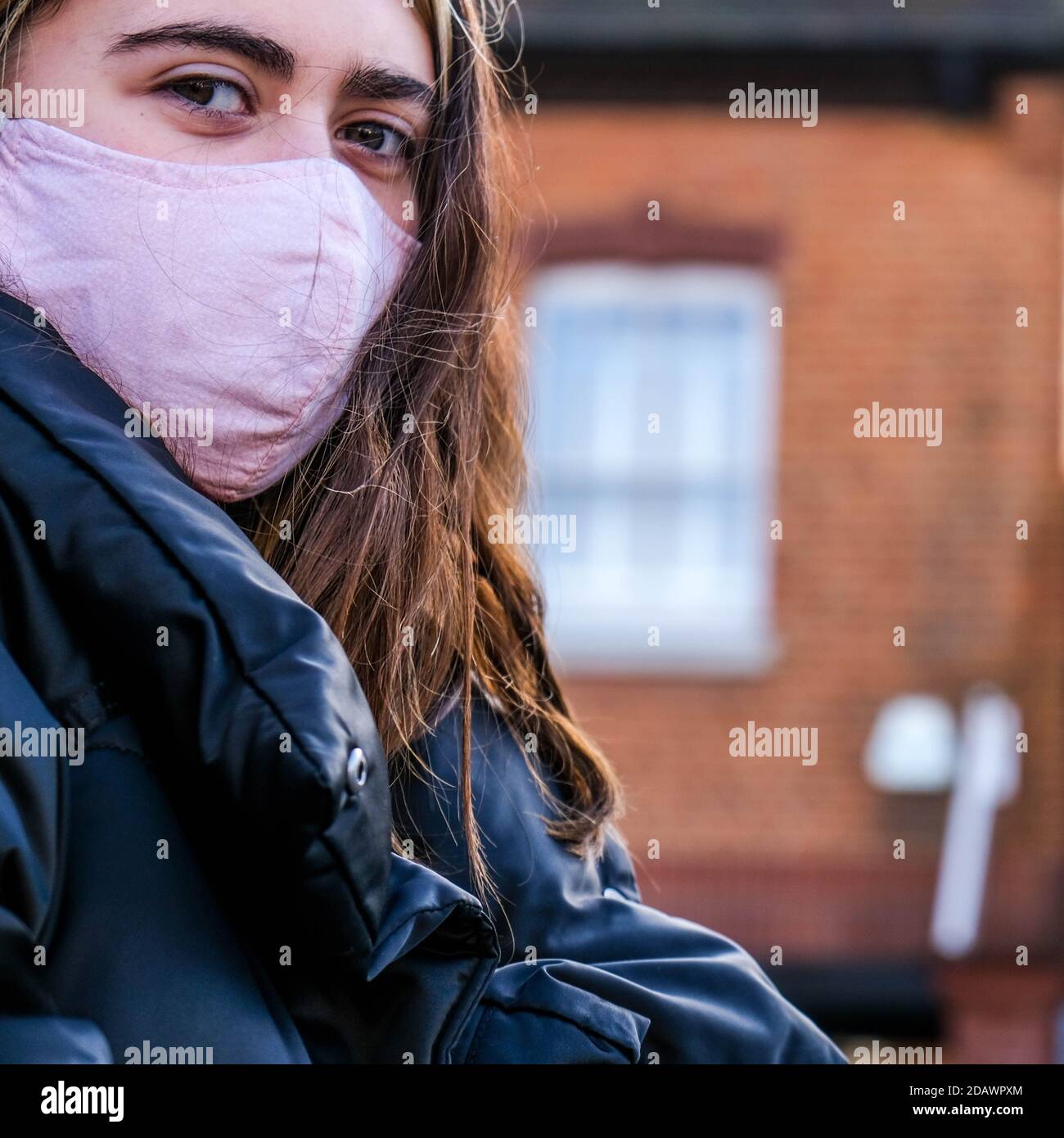 Londra UK, novembre 15 2020, Young Woman da sola indossando UNA copertura protettiva per il viso durante il COVID-19 Coronavirus Lockdown Foto Stock