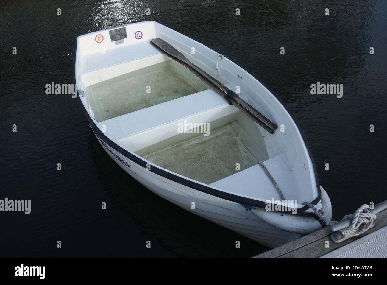 Un piccolo dinghy canottante acqua registrato togato ad un pontile in un porto turistico Foto Stock