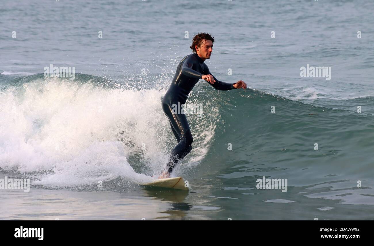 Sali a bordo di un surfista in una muta nera che cattura l'onda Foto Stock