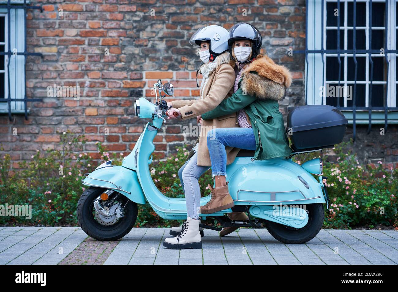 Due donne che indossano maschere e si spostano su scooter Foto stock - Alamy