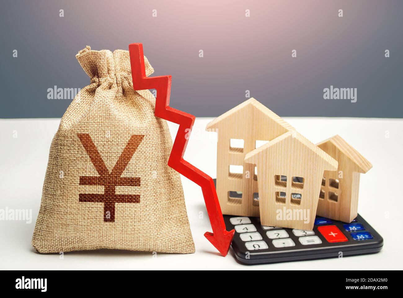 Borsa Yuan Yen con freccia in giù e case sulla calcolatrice. Risparmio di risorse e riduzione dei costi di mantenimento e dell'efficienza energetica. Immobiliare in calo ma Foto Stock