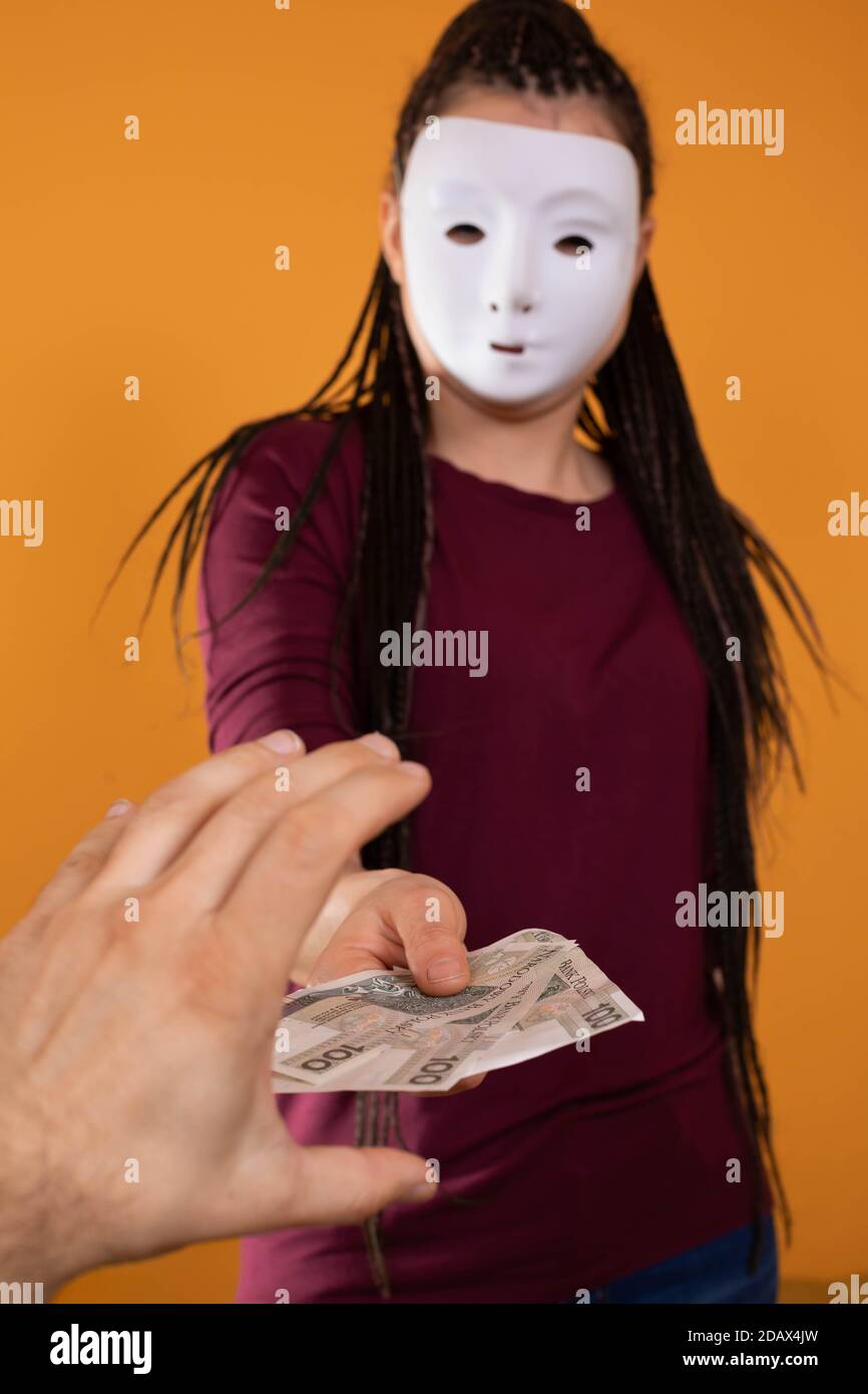 La mano maschile prende denaro da uno straniero che ha una maschera in tutto il suo volto in modo che nessuno lo riconosca. Denaro promesso in un prestito anonimo. Foto Stock