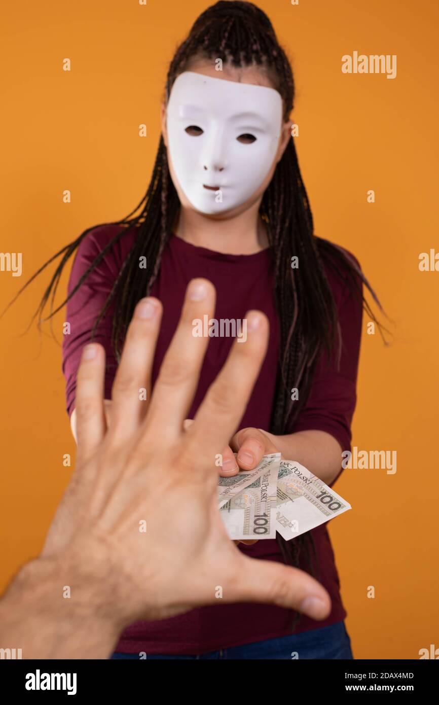 La mano maschile prende denaro da uno straniero che ha una maschera in tutto il suo volto in modo che nessuno lo riconosca. Denaro promesso in un prestito anonimo. Foto Stock
