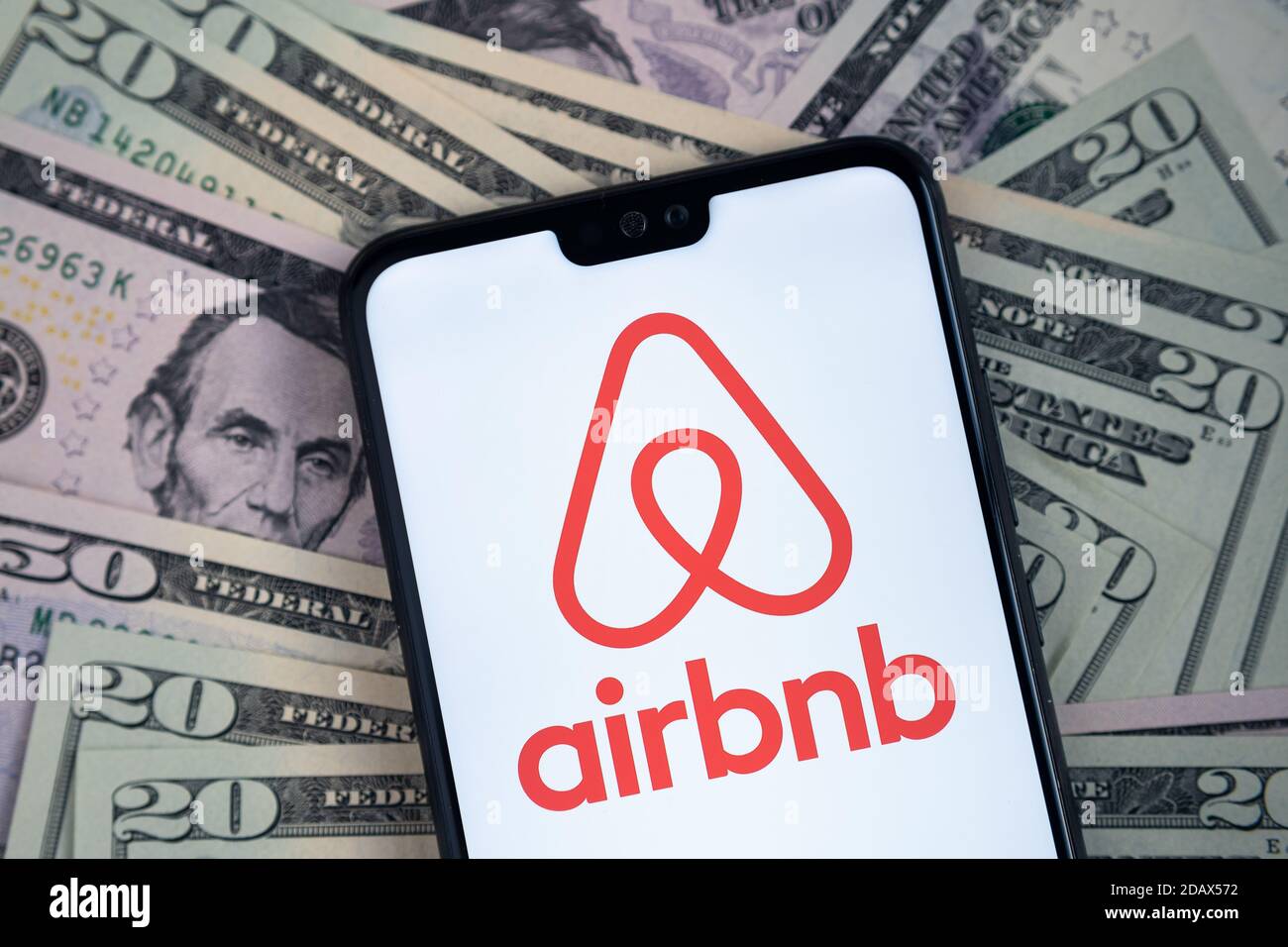 Stafford / Regno Unito - Novembre 15 2020: Il logo dell'app Airbnb visto sullo schermo dello smartphone, messo sulle bollette del dollaro. Foto Stock