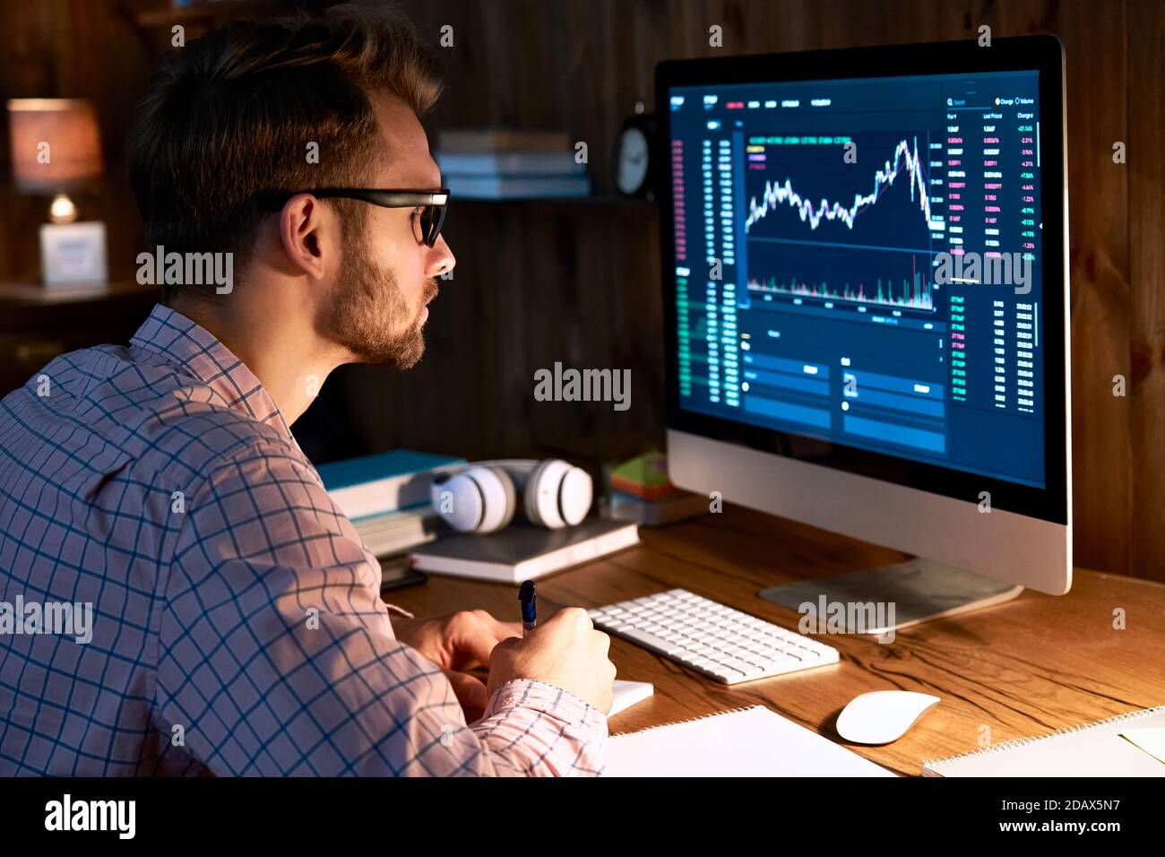 Uomo d'affari trader che osserva il pc che analizza i dati di trading di grafico finanziario. Foto Stock