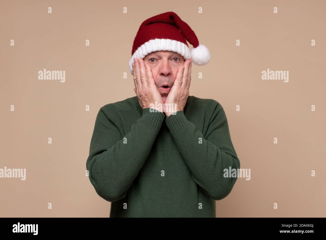 L'uomo ispanico sorpreso che indossa cappello rosso di natale che è scioccato. Foto Stock