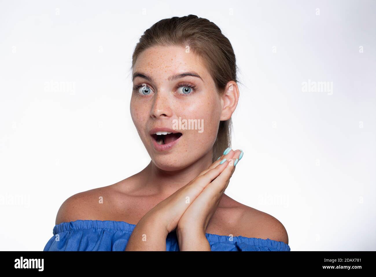 Bella ragazza con freckles mostra le emozioni di fronte al fotocamera su sfondo bianco Foto Stock