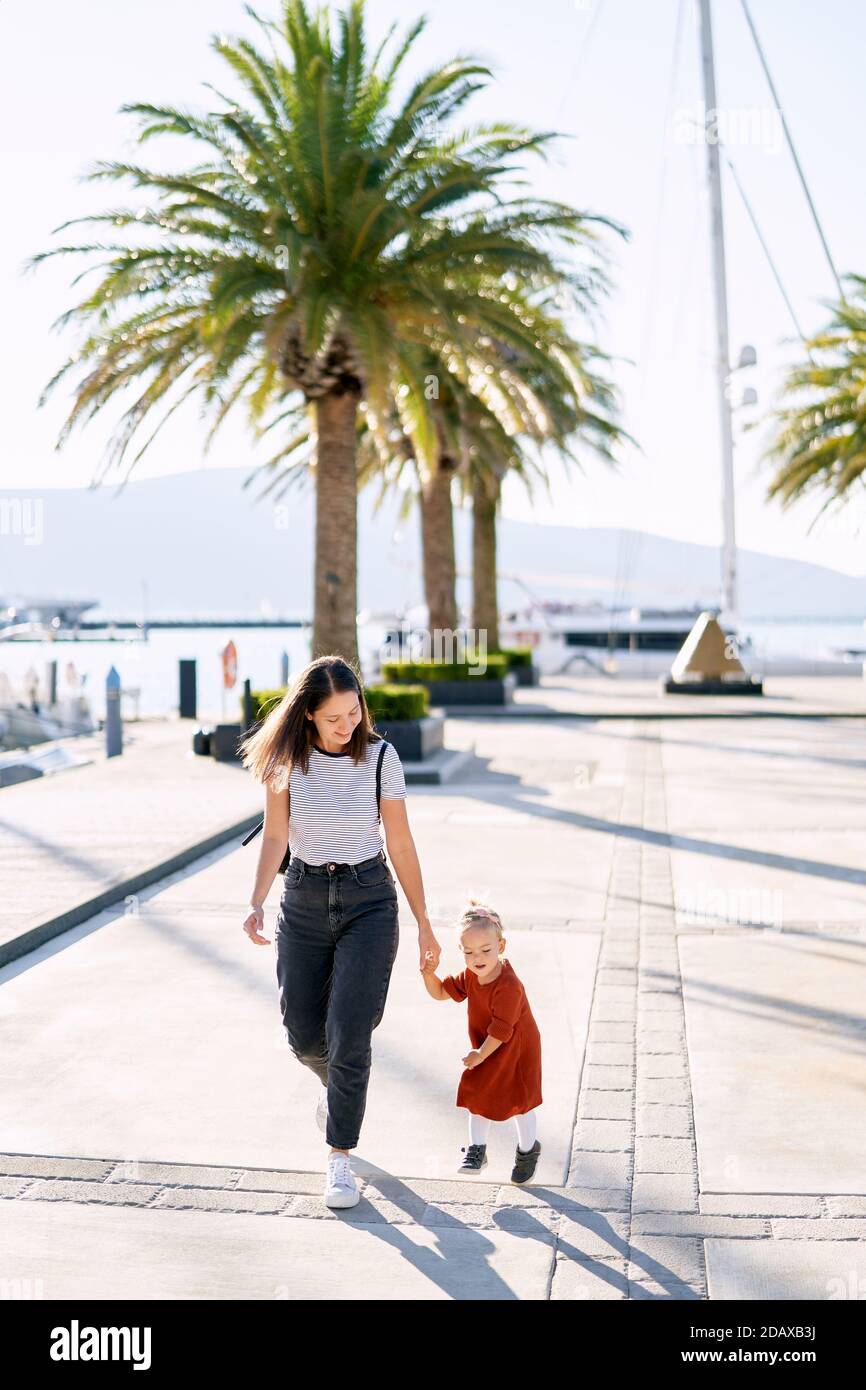 Mamma e figlia corrono e si divertono su un molo delle barche vicino al mare Foto Stock