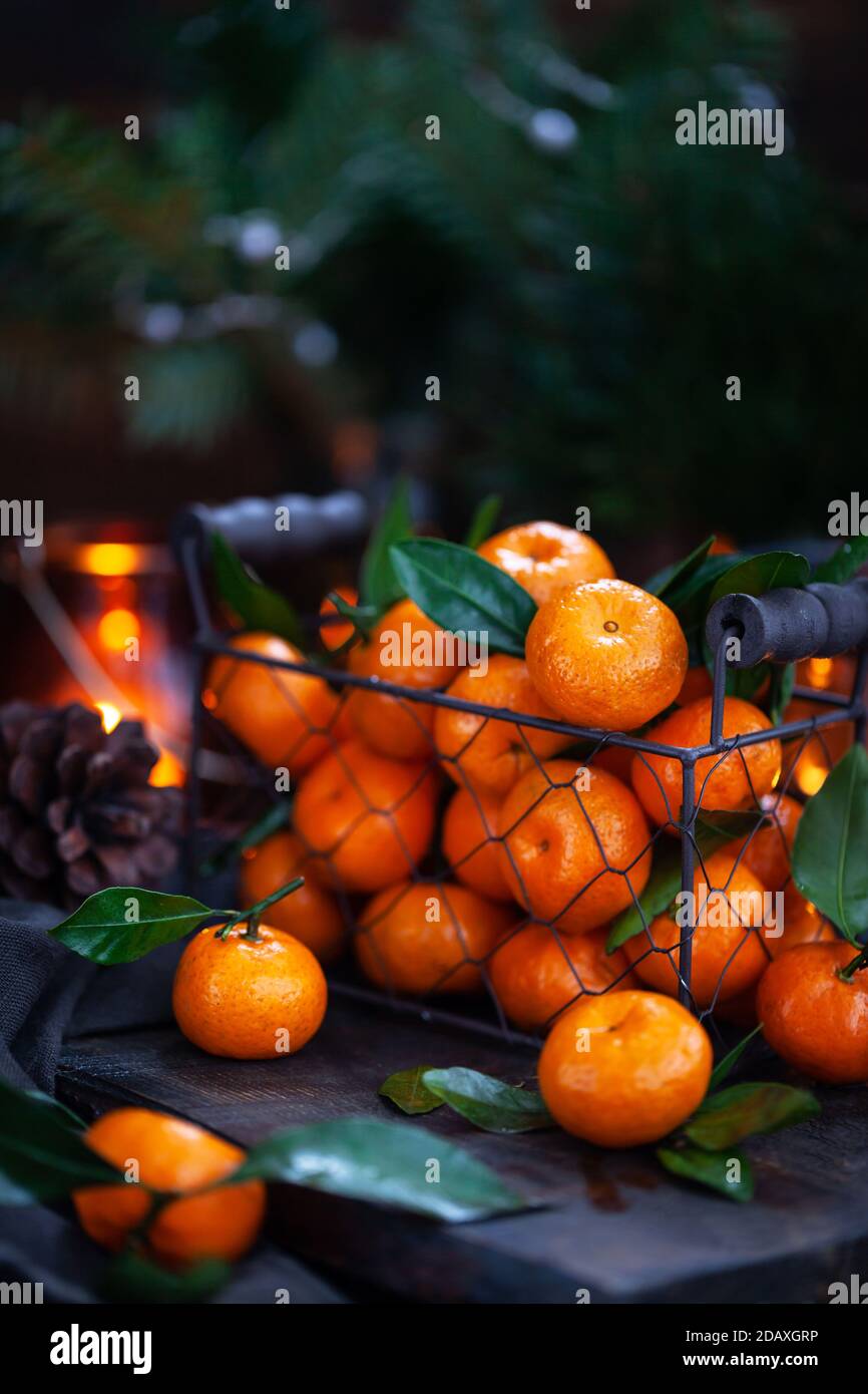Tangerini freschi maturi con foglie su tavola di legno Foto Stock