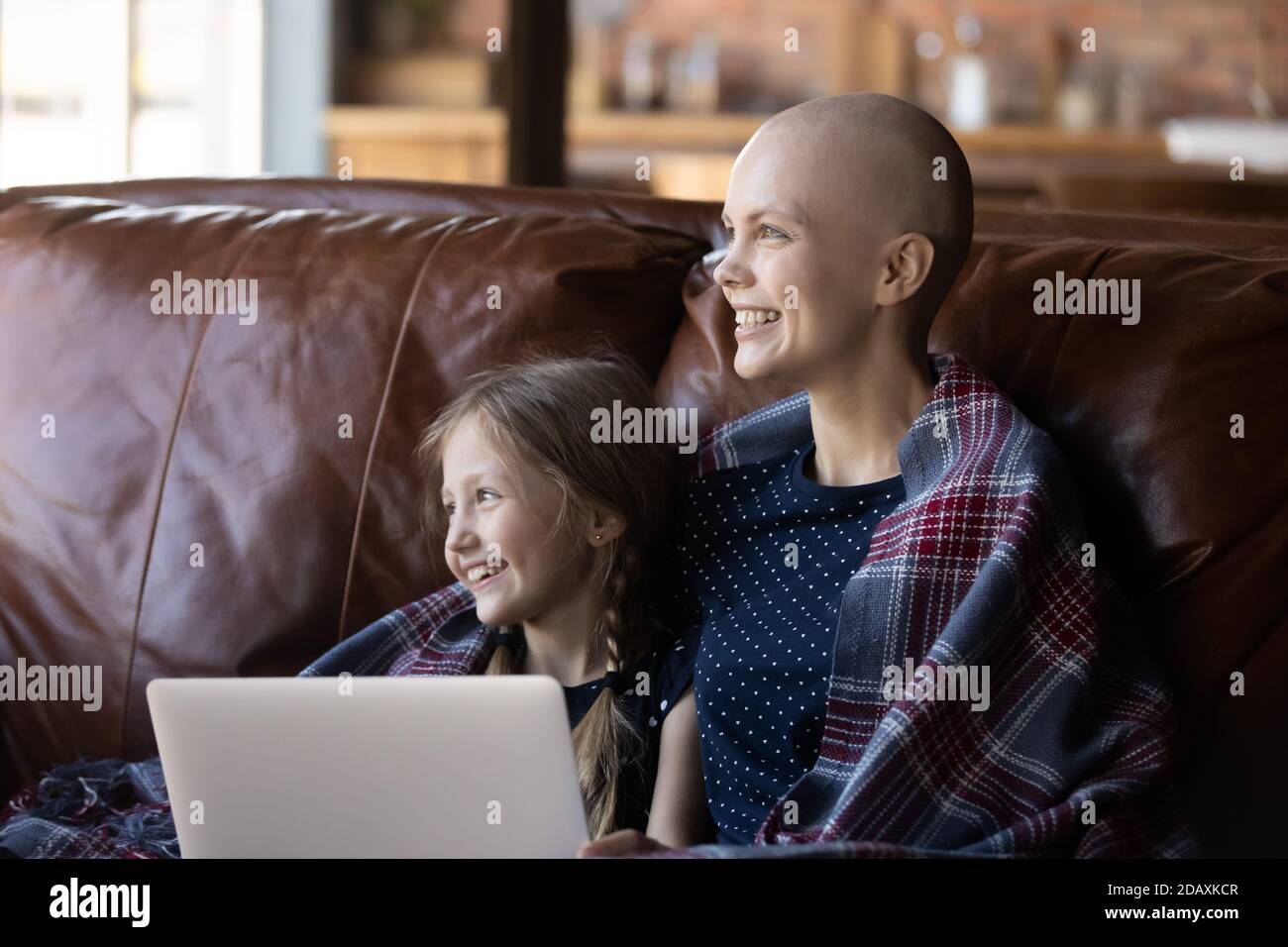 Bambina e madre malata di cancro utilizzando il computer portatile sul divano Foto Stock