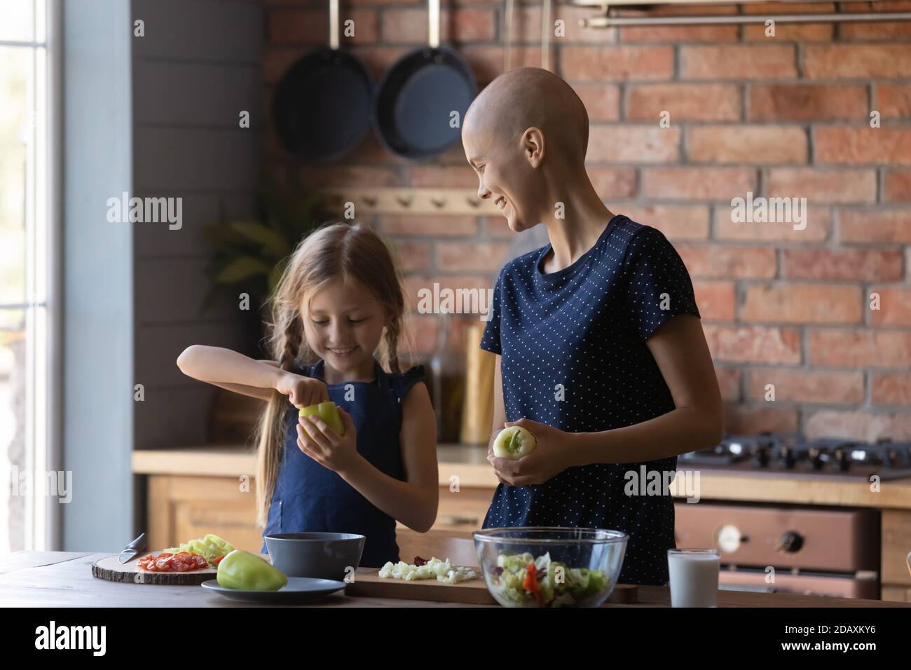 Felice madre paziente cancro e figlia che cucinano in cucina moderna Foto Stock