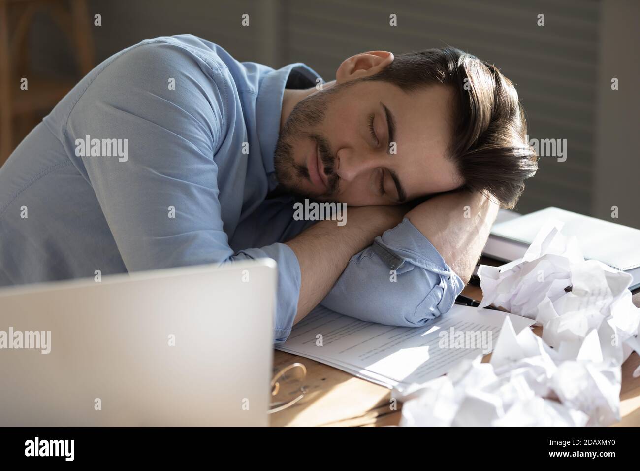 Il dipendente dell'ufficio che dormiva seduto alla scrivania si mette la testa sulle braccia Foto Stock