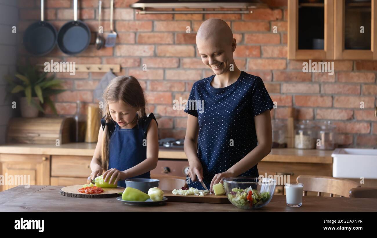 Madre concentrata recuperando dal cancro godendo di cucina insieme con la figlia Foto Stock