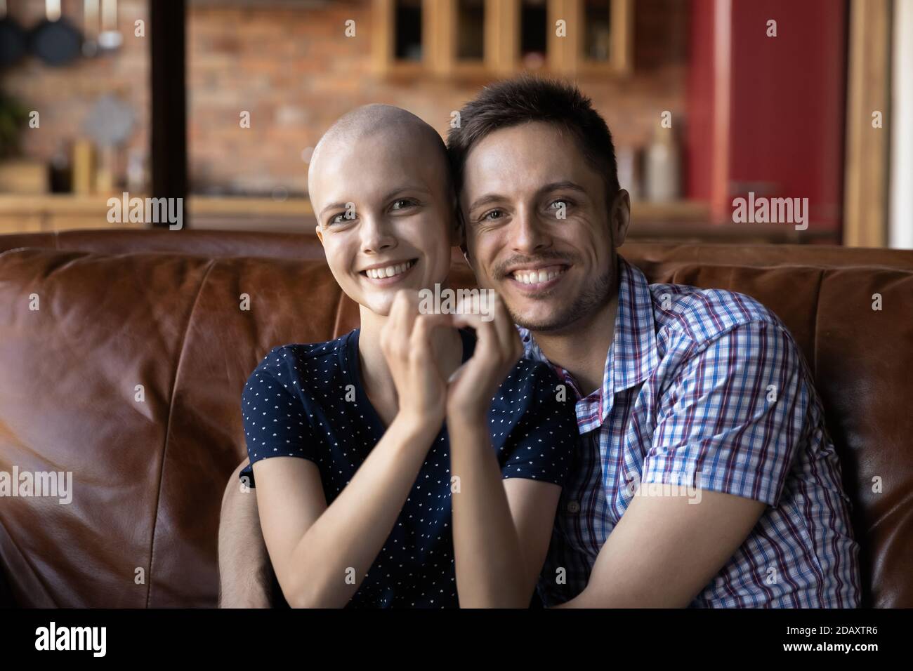 Marito amorevole abbracciare la moglie cancro paziente sul divano a casa Foto Stock