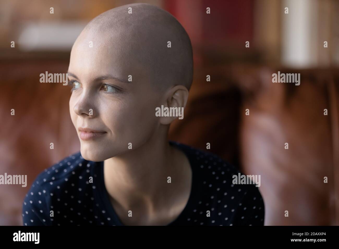 Paziente oncologico femminile pensieroso seduto sul divano guardando da parte meditare Foto Stock