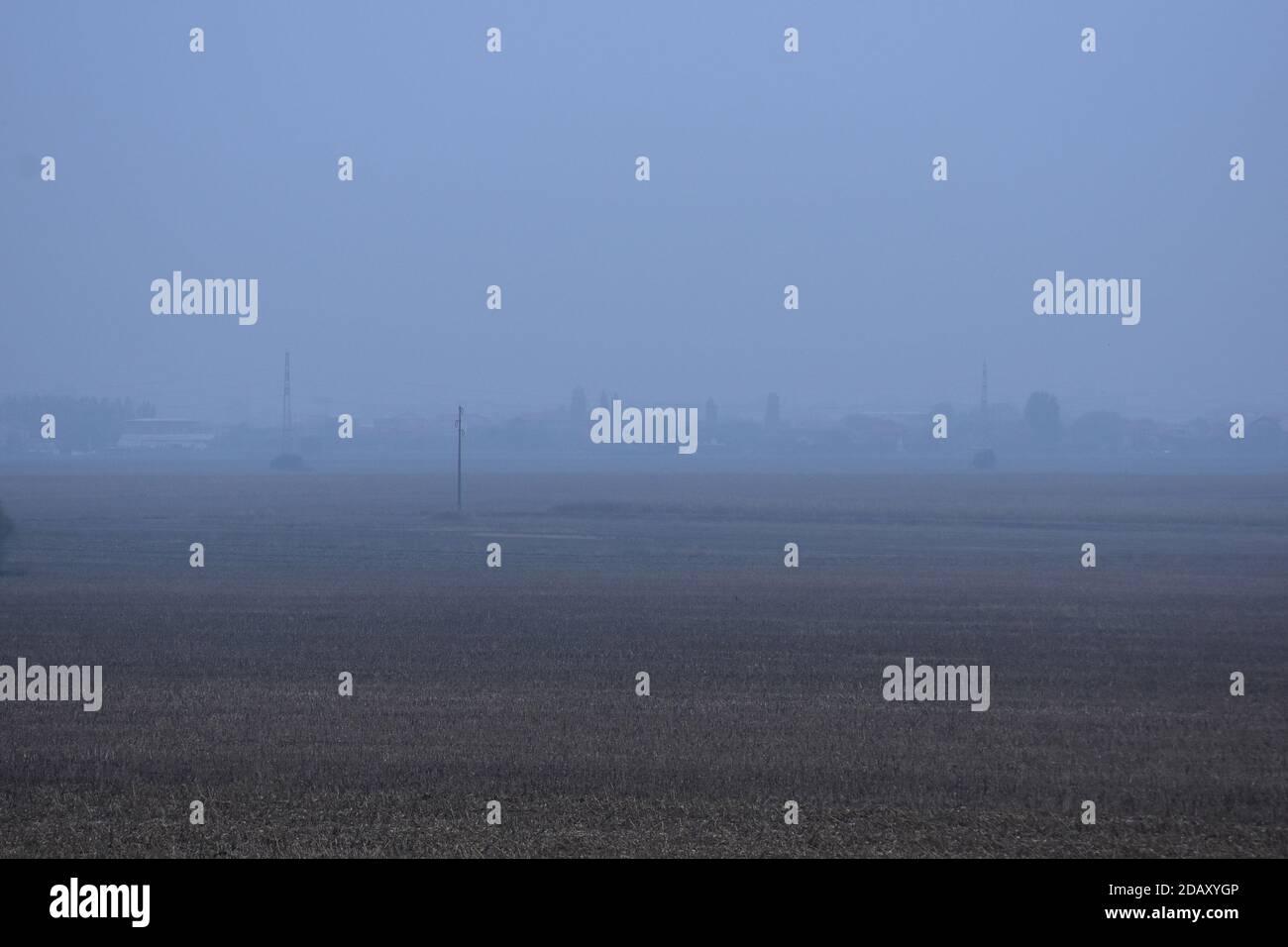 Campi vasti e fertili da cui è stato raccolto il mais. Nebbia e villaggio sullo sfondo Foto Stock