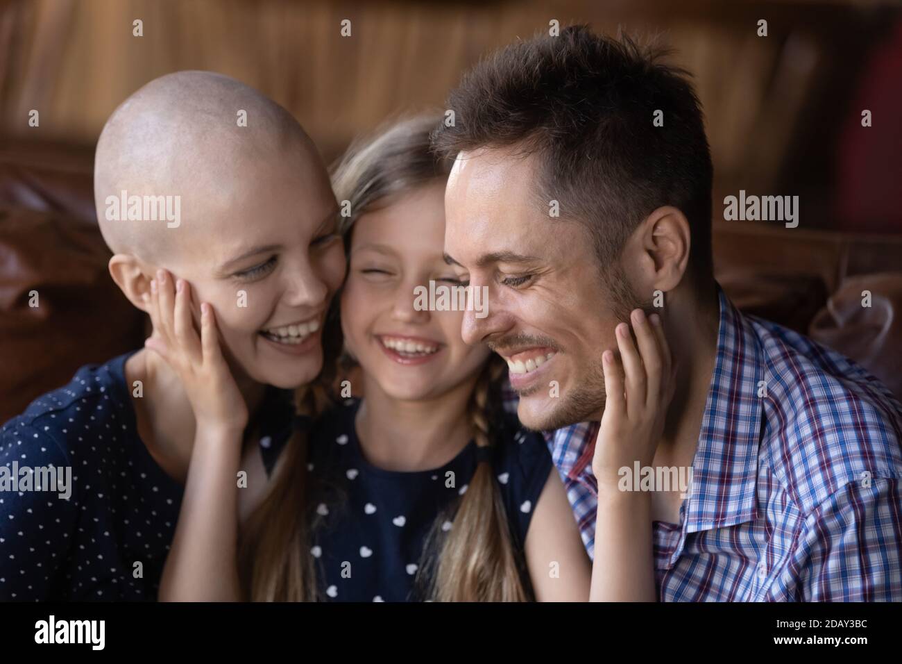 Felice piccola figlia che abbracciava padre e madre che si stava riprendendo dall'oncologia Foto Stock