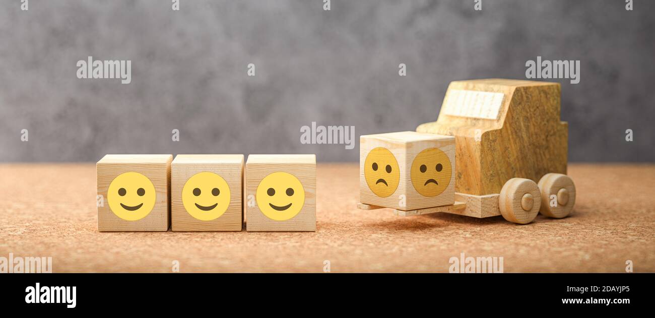 cubi con emoticon felici e un carrello elevatore che ne porta un altro con un sorriso triste su sfondo concreto - illustrazione 3d Foto Stock