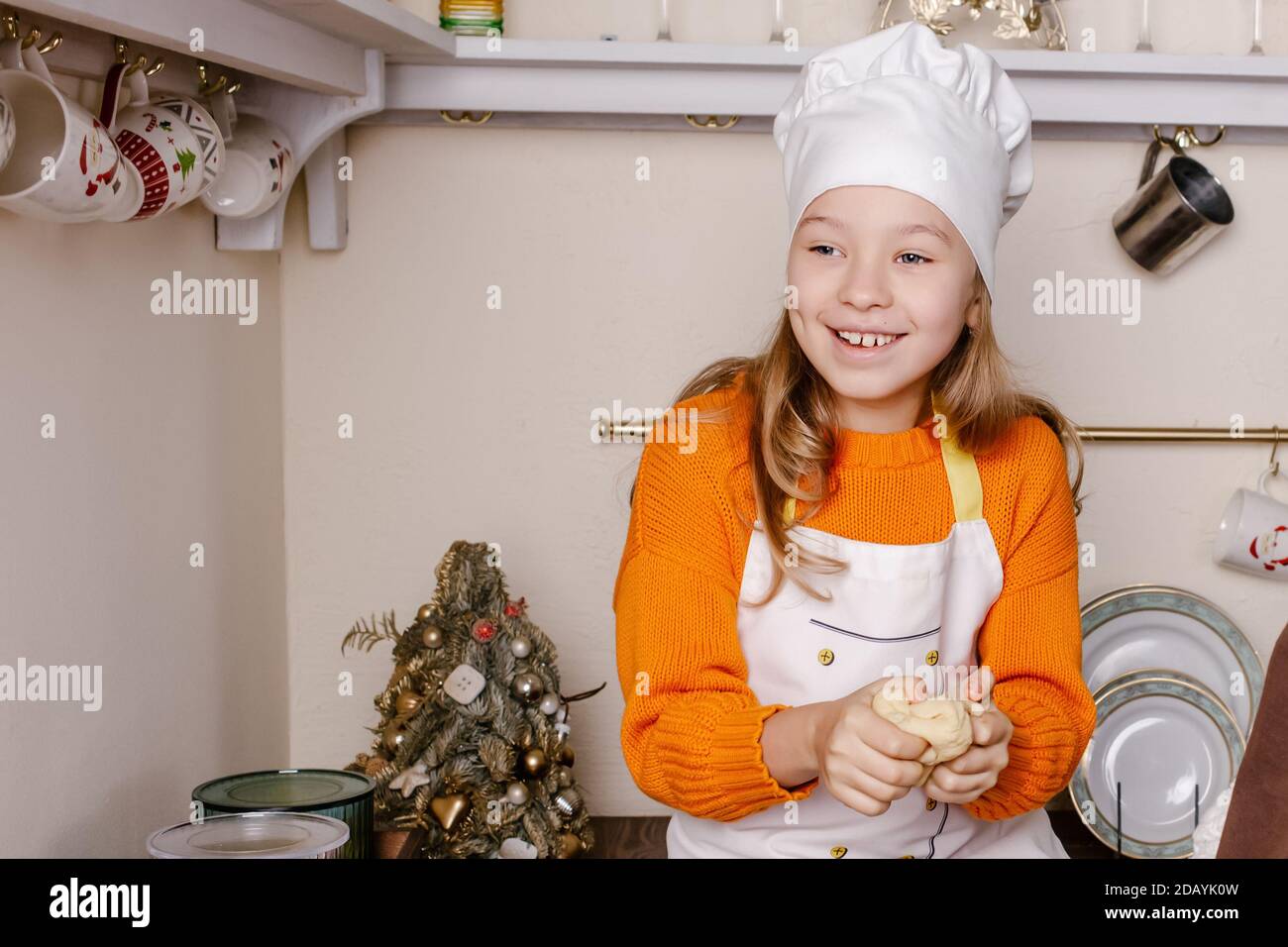 Bambina che fa il pan di zenzero di Natale alla cucina nel soggiorno decorato. Cottura e cottura con i bambini per Natale a casa. Foto Stock