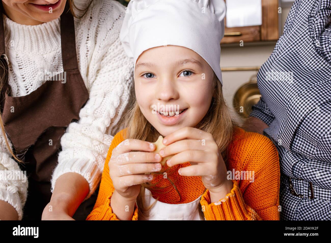 La famiglia prepara biscotti di pan di zenzero in cucina. Nonna, mamma e figlia cuocere i biscotti in cucina e decorare i biscotti la vigilia di Natale. Foto Stock