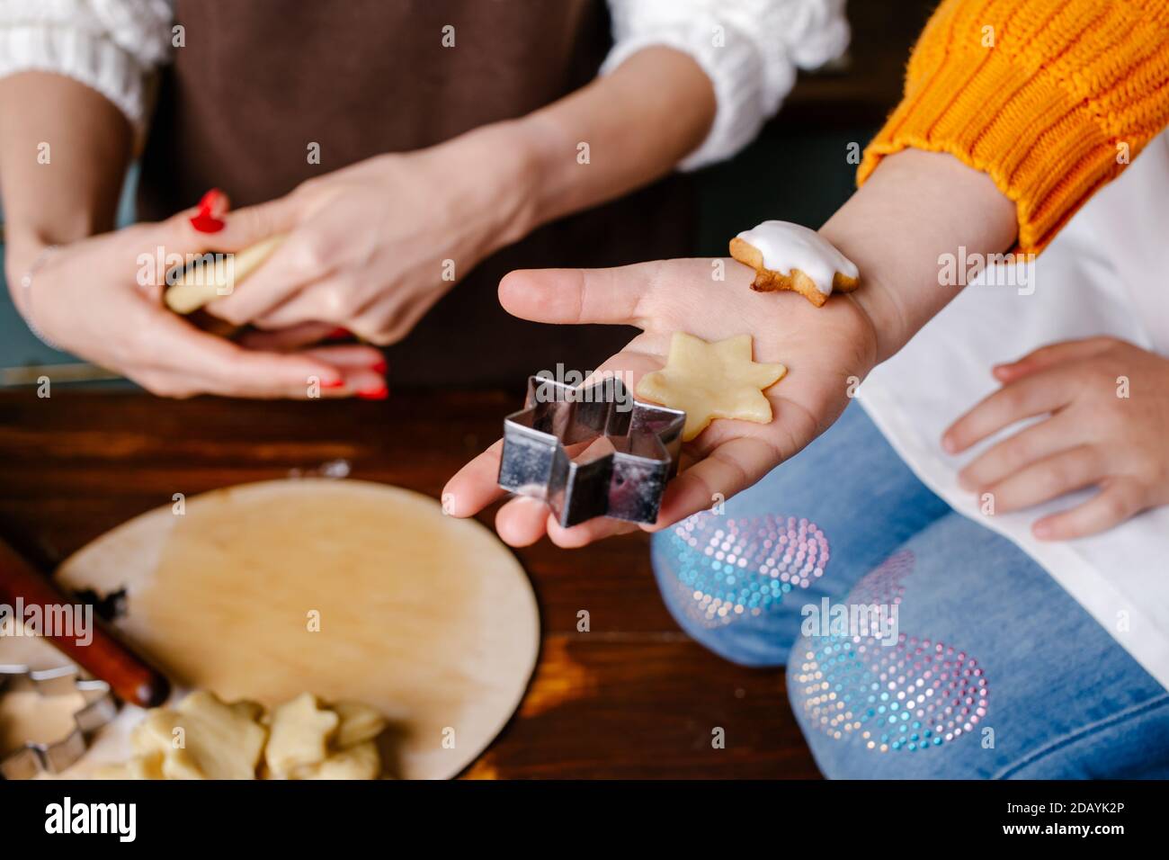 La mano della bambina che fa i biscotti tradizionali di Natale. Preparare gli uomini di pan di zenzero di Natale. Fasi di preparazione dei biscotti. Vista dall'alto. Foto Stock