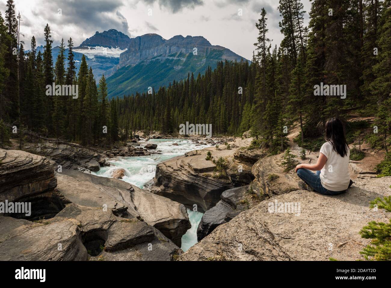 Donna seduta sulle rocce che si rilassa nel Mistaya Canyon nel Jasper National Park, Alberta, Canada. Foto Stock