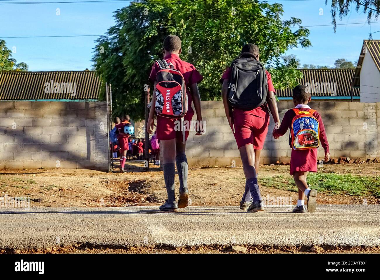 I bambini attraversano la strada per raggiungere la scuola elementare di Jahunda a Gwanda, Zimbabwe. Foto Stock