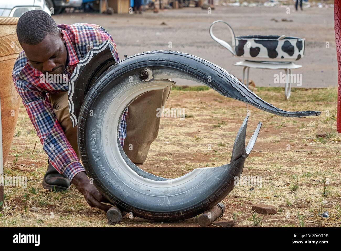 Al Centro commerciale Kamfinsa di Harare, Zimbabwe, David Mutasa crea un'opera d'arte che ha realizzato con un pneumatico. Foto Stock