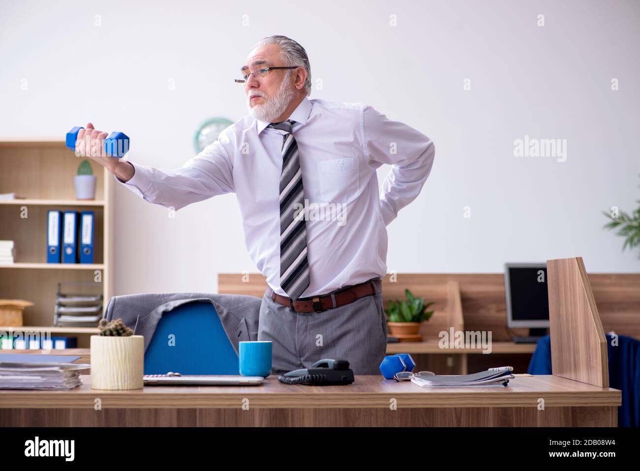 Anziano dipendente che soffre di radicolite sul posto di lavoro Foto Stock