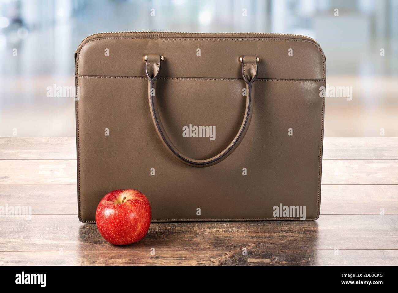 borsa da lavoro, valigetta e mela rossa su un tavolo di legno su