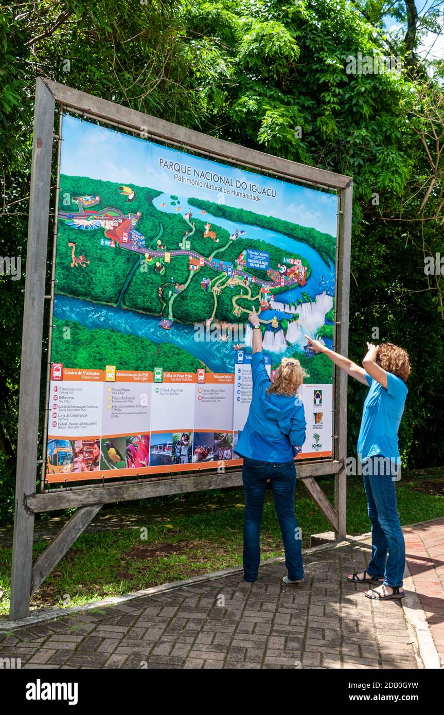 Due visitatori che guardano una grande mappa delle cascate e dei sentieri per i piedi nel Parco Nazionale di Iguazu dell'Argentina. Foto Stock