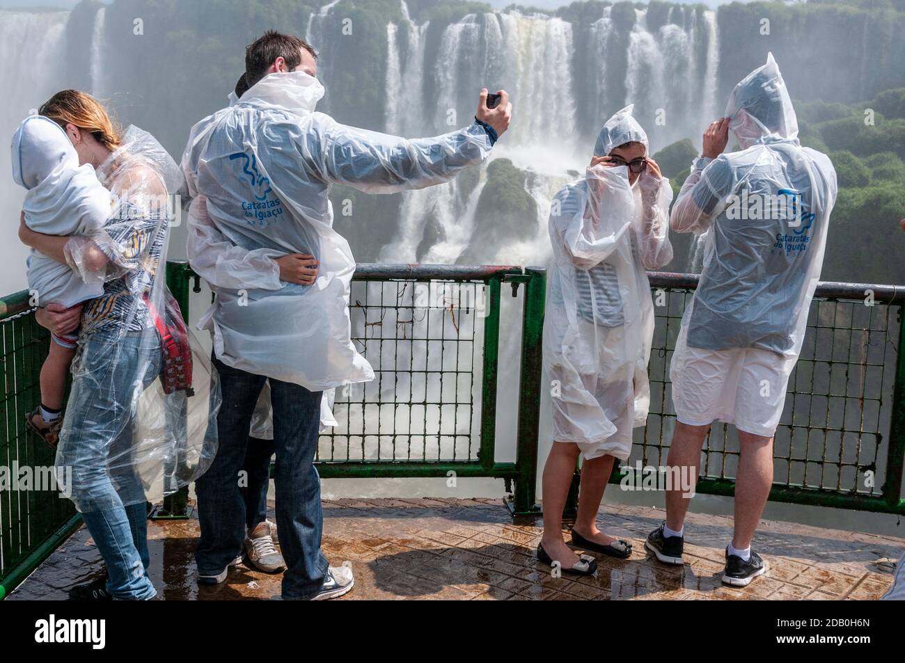 I visitatori che indossano cappotti di plastica per l'acqua dallo spray sulla piattaforma di osservazione sul lato brasiliano delle cascate di Iguazu in Brasile. Foto Stock