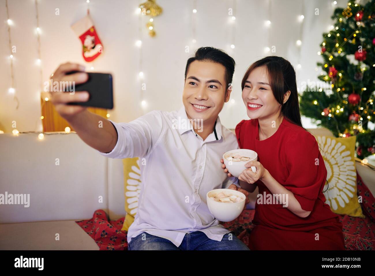 Coppia che prende selfie con tazze di cacao Foto Stock