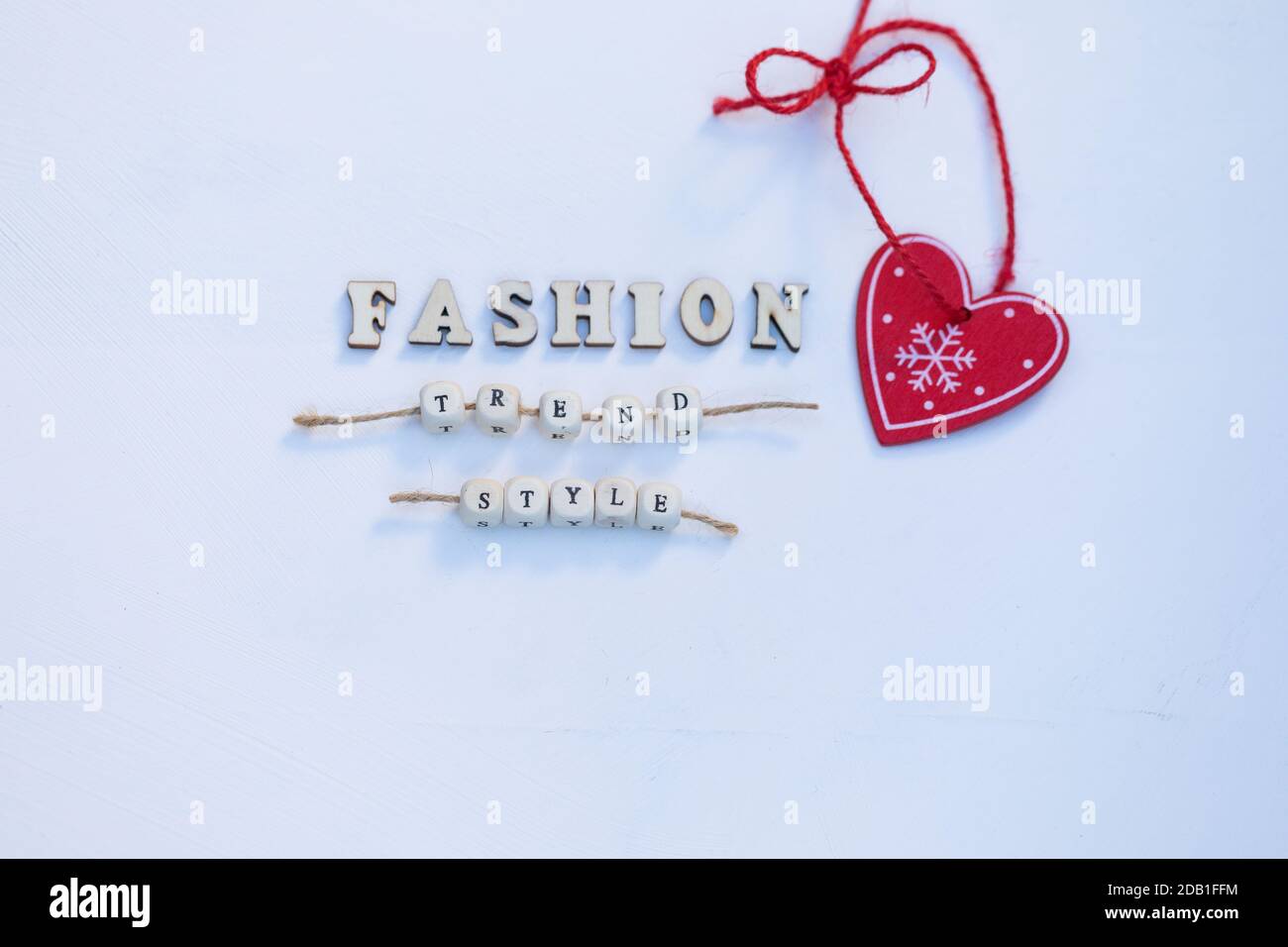 Cuore rosso albero di Natale decorazione e parole Moda, tendenza, stile sono su Eco legno bianco sfondo. Vista dall'alto Flat Lay. Foto Stock