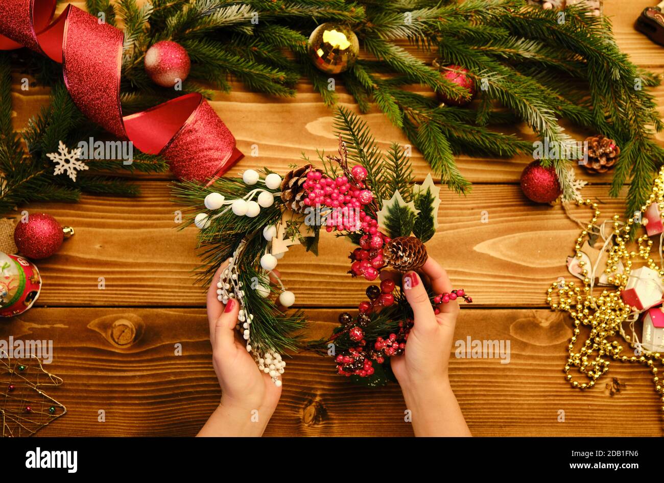 Mani che fanno la corona di Natale rustica s su uno sfondo di legno. Immagine della moodia atmosferica al workshop di vacanza Foto Stock
