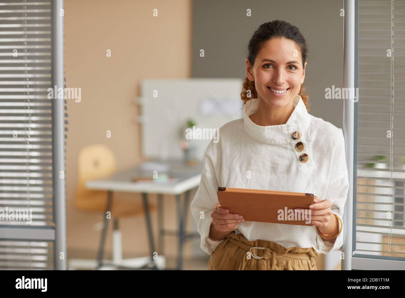 Ritratto in vita di una donna d'affari sorridente di successo che guarda la fotocamera e tiene un tablet digitale mentre lavora da casa, copia spazio Foto Stock