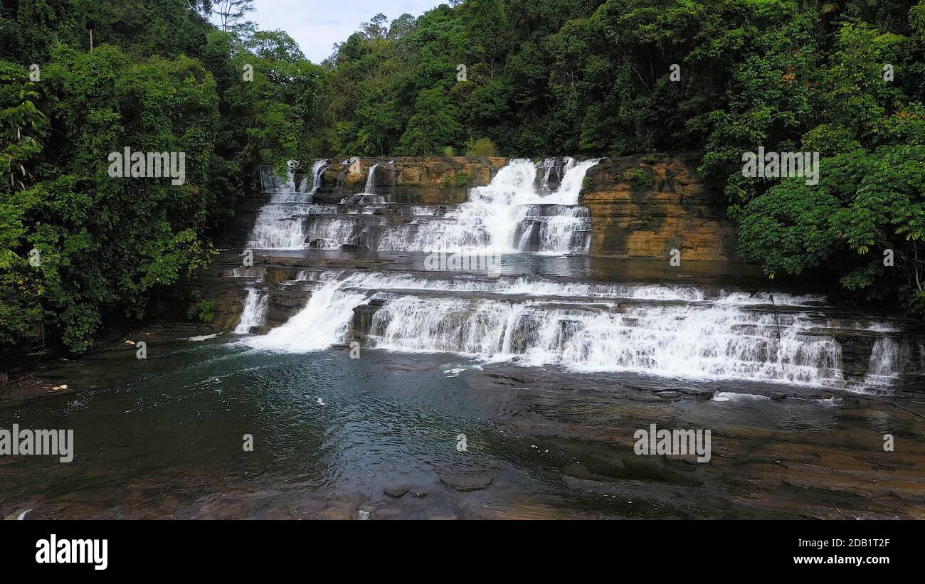 Veduta aerea dall'alto della giungla cascata in una foresta tropicale circondata da vegetazione verde. Cascate di Tinuy-an nella giungla di montagna. Filippine, Mindanao. Foto Stock