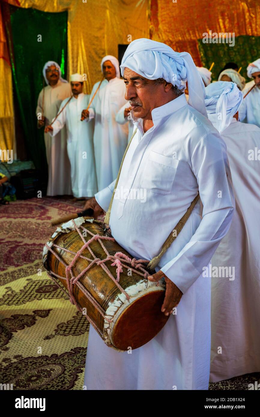 Gli uomini in abito tradizionale suonano lo strumento locale durante una tradizionale cerimonia nuziale a bandar-e kong, nella provincia di Hormozgan in Iran. Foto Stock