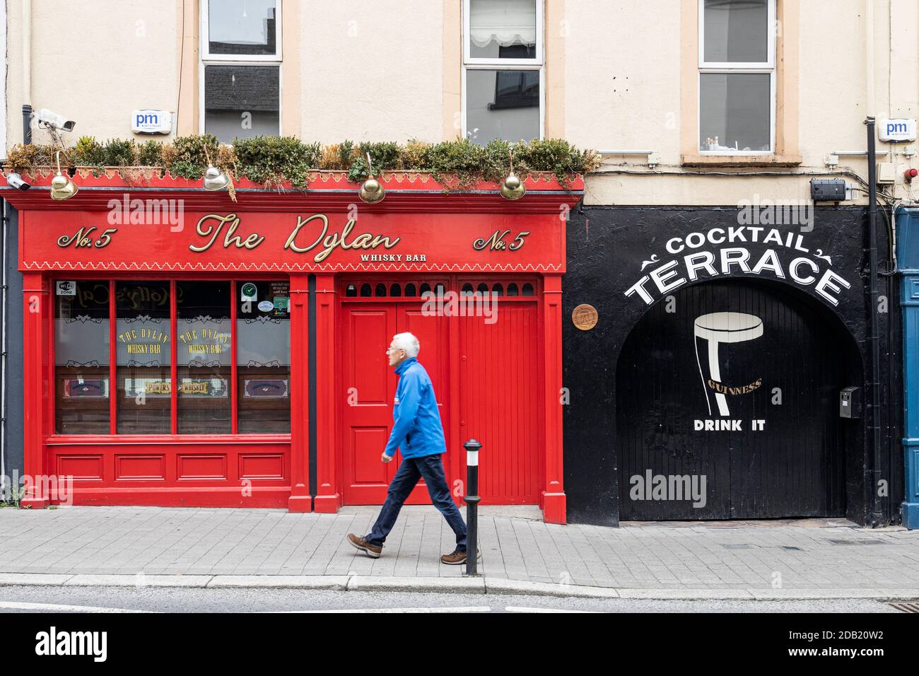 L'uomo cammina vicino al whisky bar Dylan e alla terrazza cocktail con pubblicità Guinness, Kilkenny, County Kilkenny, Irlanda Foto Stock L'uomo cammina vicino al whisky bar Dylan e alla terrazza cocktail con pubblicità Guinness, Kilkenny, County Kilkenny, Irlanda Foto Stock