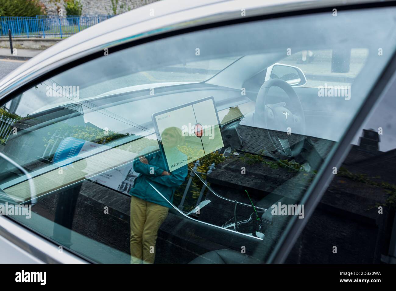 Sentry ha attivato l'avvertimento sullo schermo di un'auto Tesla come una donna si avvicina guardando sopra, visto attraverso il finestrino laterale, County Kilkenny, Irlanda Foto Stock