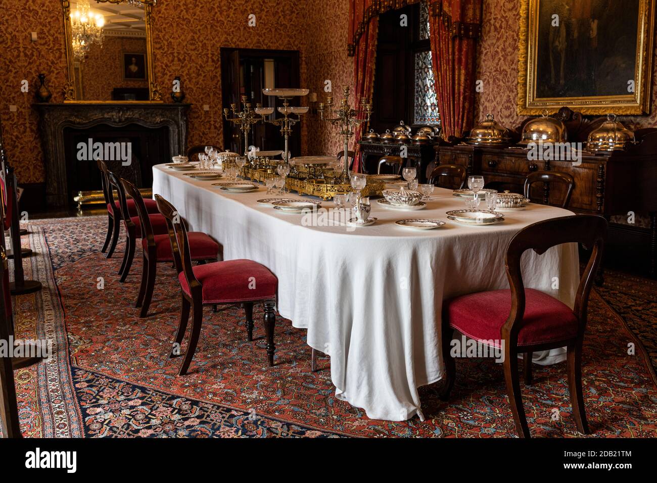 Sala da pranzo con tavolo, carta da parati bloccata a mano sulle pareti e lampadari di cristallo nel castello di Kilkenny, County Kilkenny, Irlanda Foto Stock