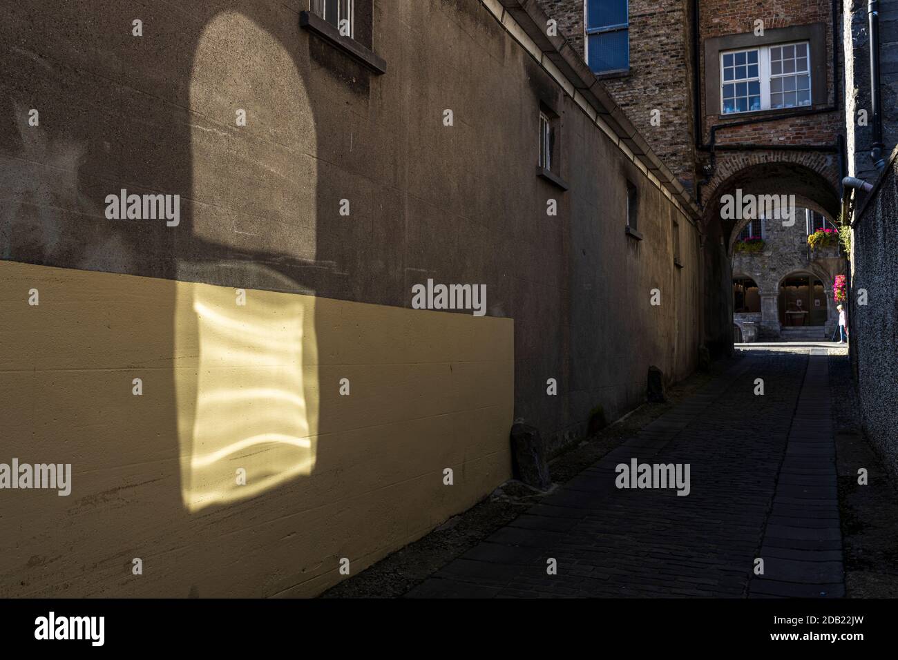 La luce riflessa getta una forma astratta su un muro in un vicolo a Kilkenny, County Kilkenny, Irlanda Foto Stock