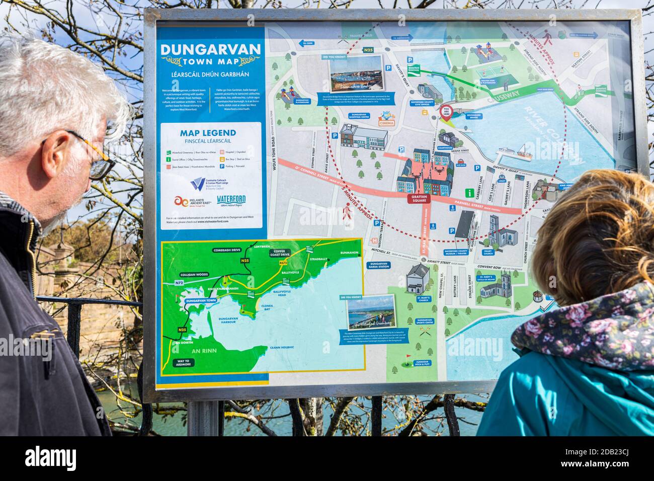 I visitatori che leggono un cartello e una mappa di informazioni turistiche a Dungarvan, County Waterford, Irlanda, Foto Stock