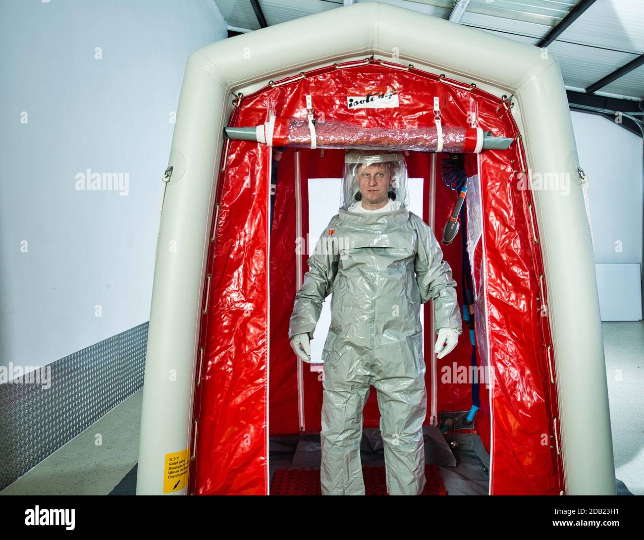 Uomo che indossa una tuta di decontaminazione in piedi in una tenda di decontaminazione Foto Stock