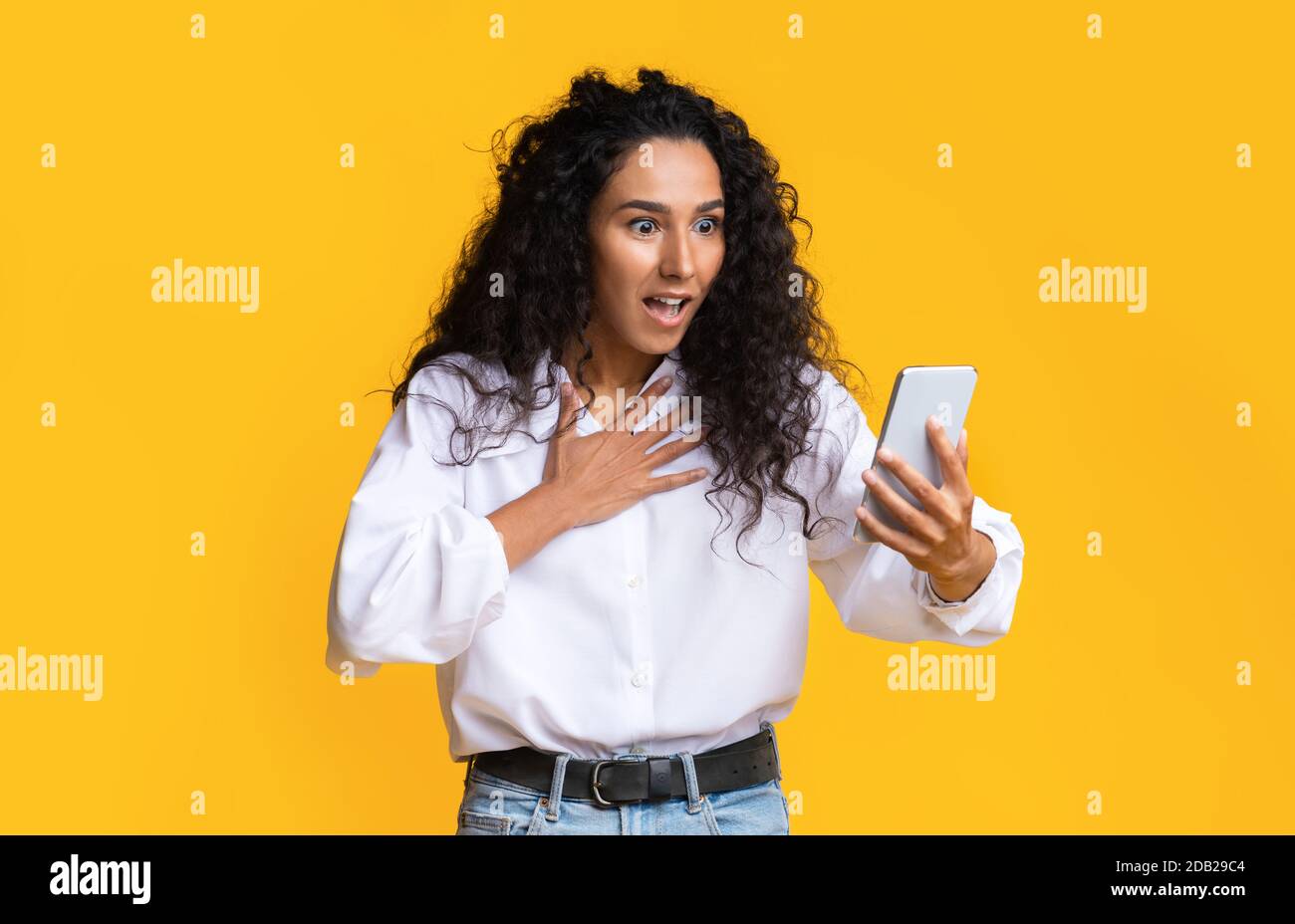 OMG. Brunette Lady sconvolta che guarda lo schermo dello smartphone con sorpresa Face Expression Foto Stock