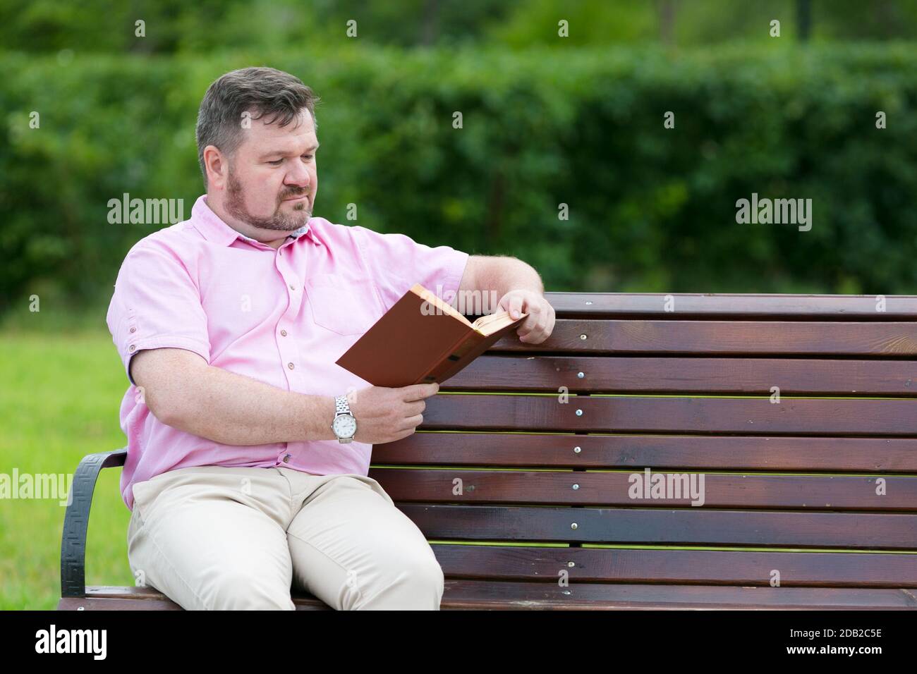 Un uomo in groppa sta leggendo un libro sulla panchina. Spazio di copia. Foto Stock