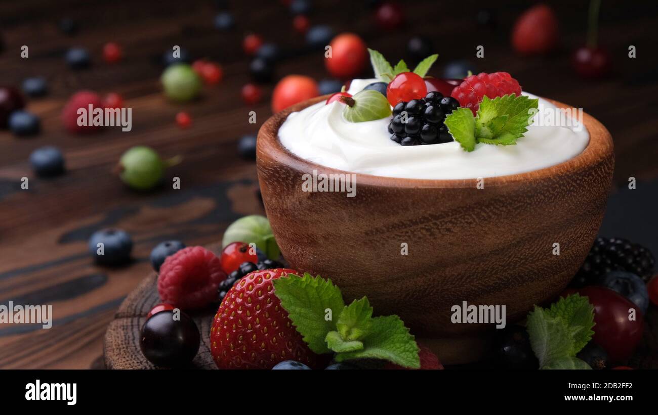 Yogurt con frutti di bosco su sfondo di legno scuro Foto Stock