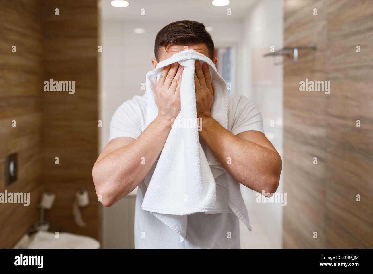 L'uomo gli asciuga il viso con un asciugamano, vista frontale, igiene  mattutina di routine. La