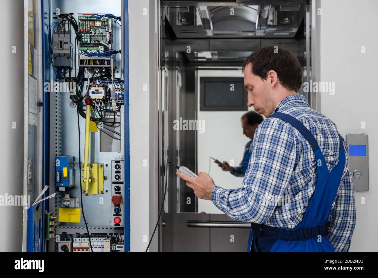 Riparazione Da Parte Del Tecnico Del Pannello Di Controllo Dell'Elevatore Rotto Foto Stock